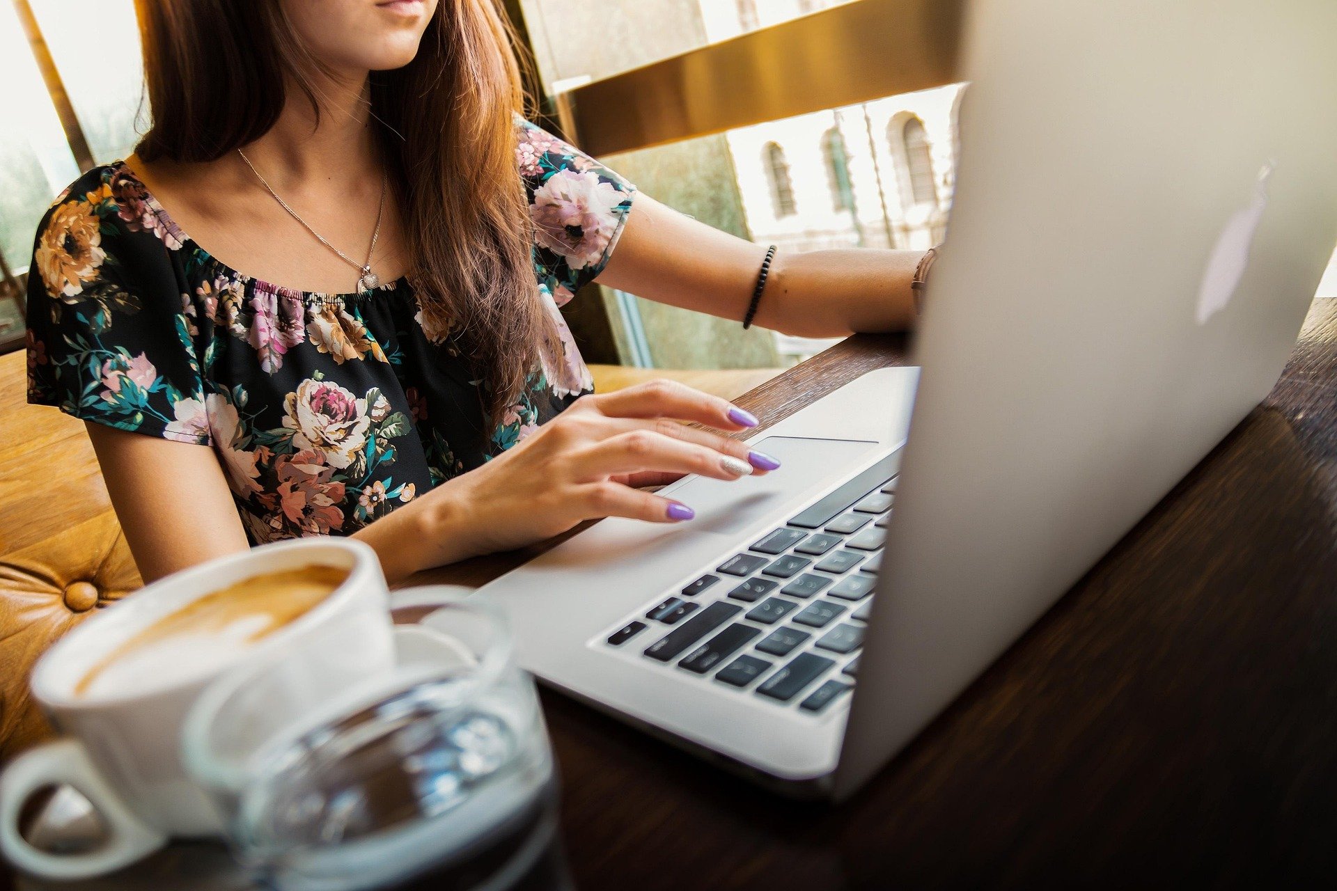 kobieta siedząca przed laptopem apple macbook