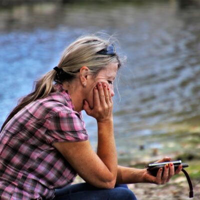 Smutek, depresja, infolinia, telefon, kobieta nad jeziorem, potrzebna pomoc