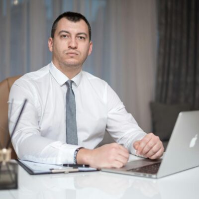 mężczyzna siedzący przed laptopem firmy Apple
