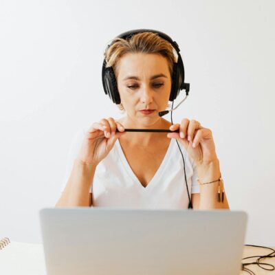 kobieta siedząca przed laptopem ze słuchawkami na uszach telemarketerka