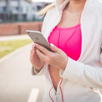 Kobieta z iPhonem, smartfonem Apple i słuchawkami wyszła na jogging, uprawia sport
