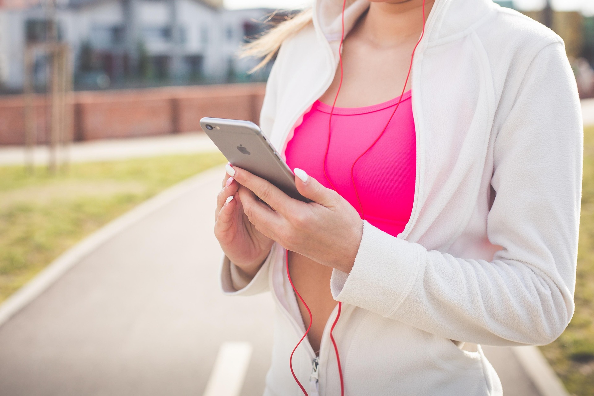 Kobieta z iPhonem, smartfonem Apple i słuchawkami wyszła na jogging, uprawia sport