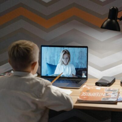 chłopiec siedzący i uczący się przed laptopem; lekcja zdalna