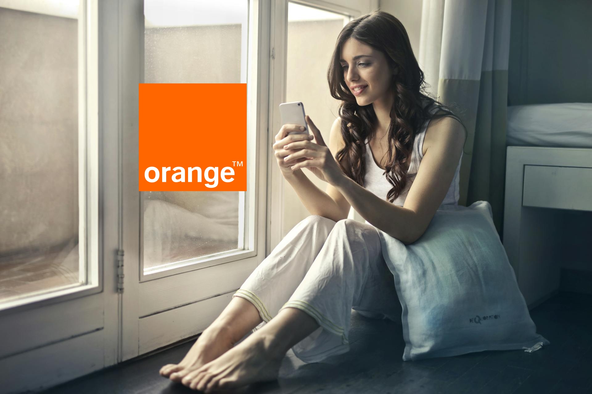dziewczyna trzymająca smartfon obok logo orange
