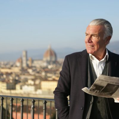 starszy mężczyzna z gazetą w ręce na tle Florencji