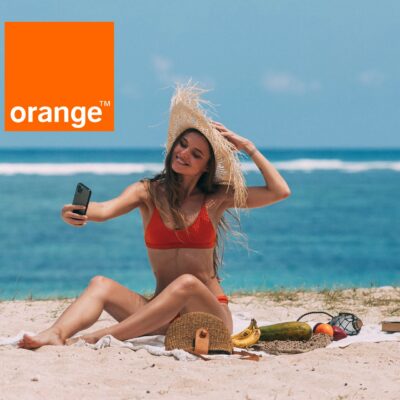 dziewczyna na plaży ze smartfonem w ręce, obok logo orange