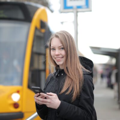 kobieta, zadowolona, smartfon, telefon, przystanek, autobus
