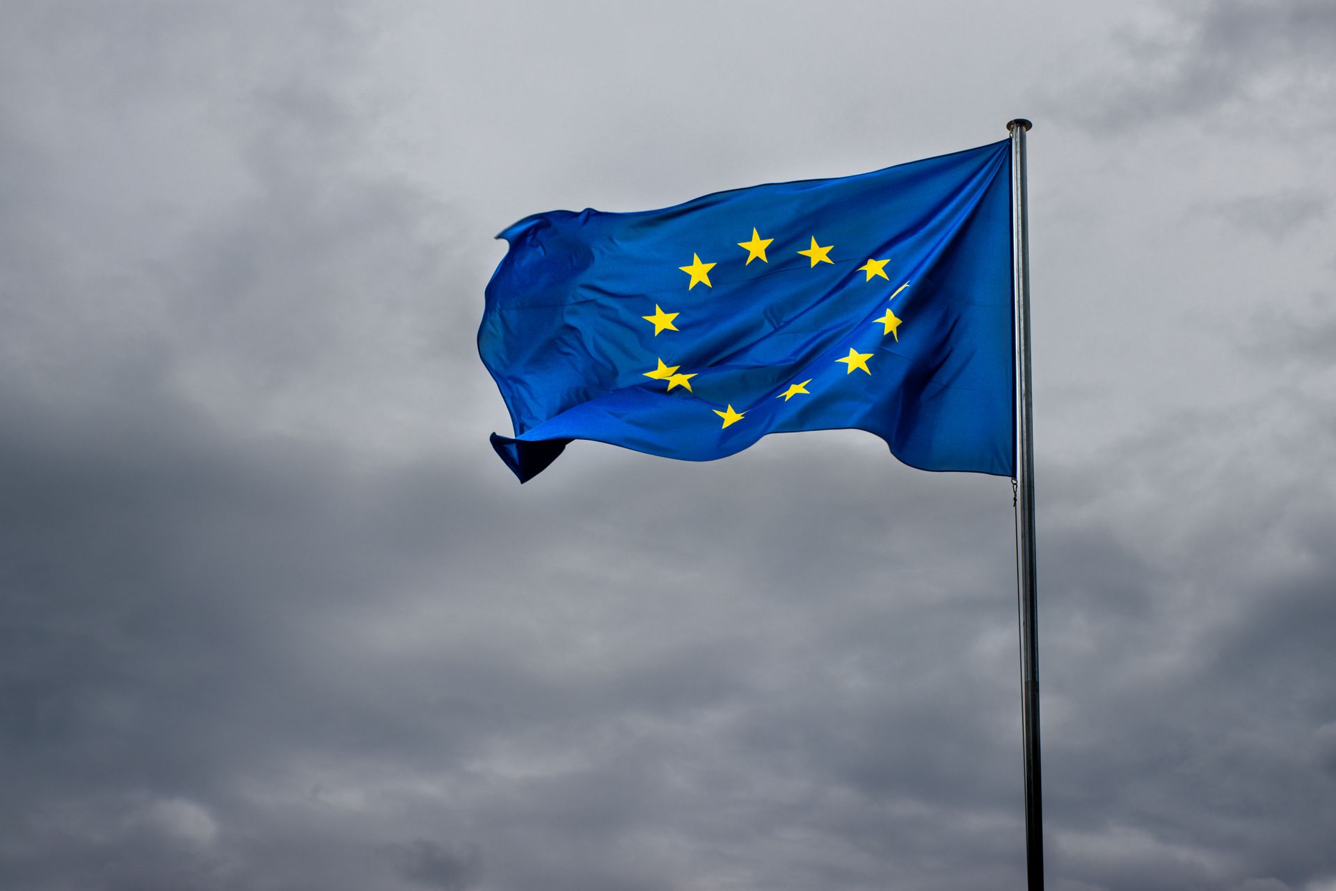 flaga unii europejskiej na tle zachmurzonego ciemnego nieba
