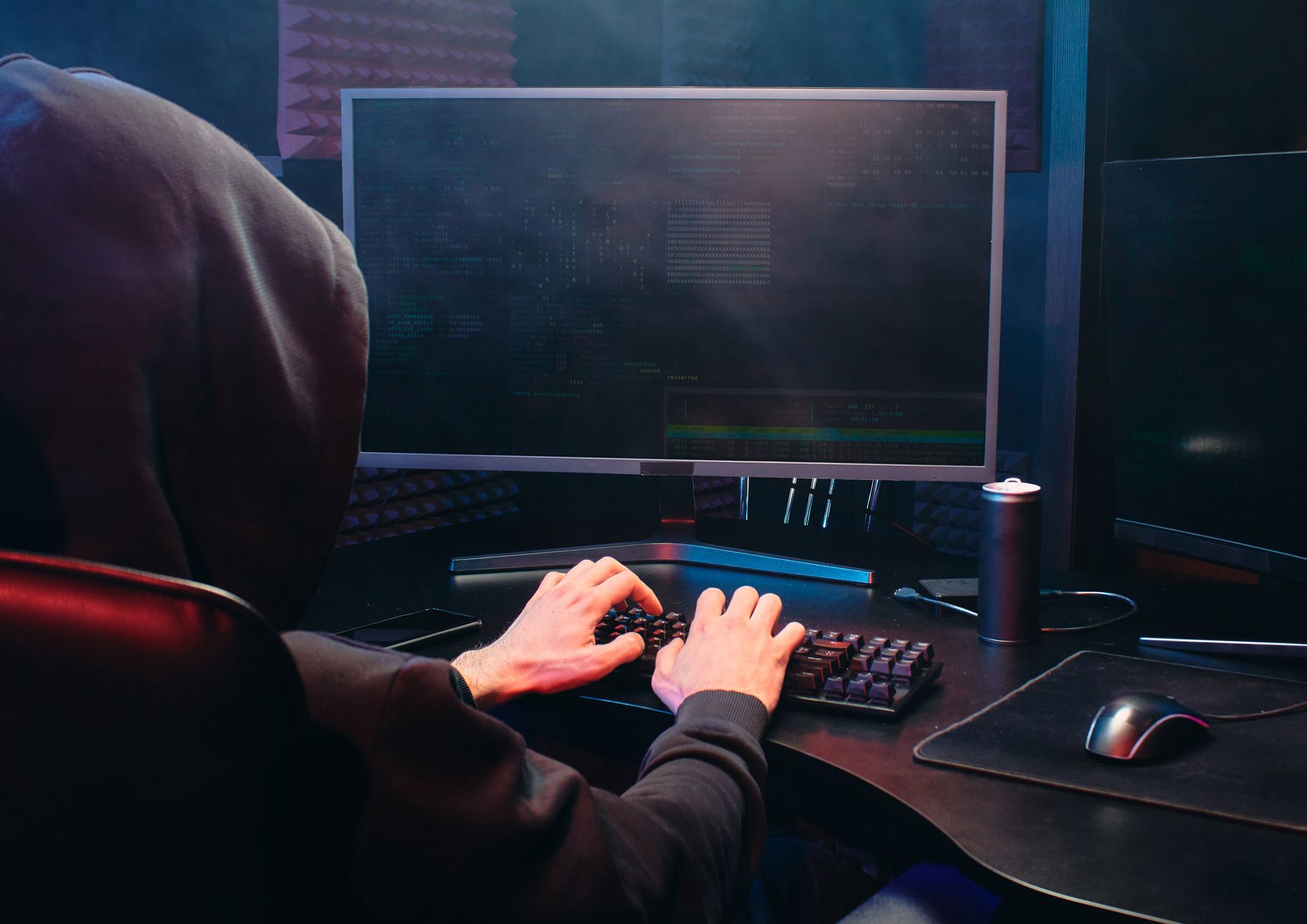 haker hacker siedzący przed komputerem w bluzie z kapturem na głowie