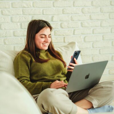uśmiechnięta młoda kobieta dziewczyna z laptopem i smartfonem w ręce