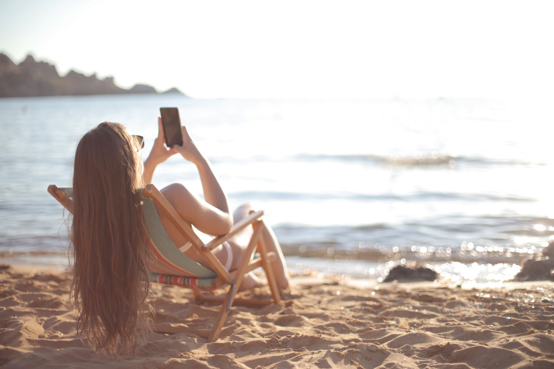 kobieta dziewczyna na plaży z telefonem smartfonem w ręce
