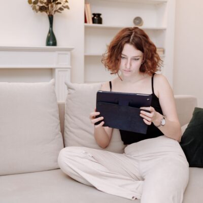 dziewczyna z tabletem w rękach siedząca na kanapie w salonie